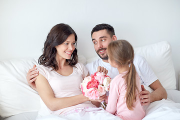 Image showing happy girl giving flowers to mother in bed at home