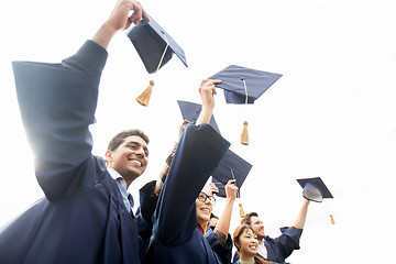 Image showing happy students or bachelors waving mortar boards