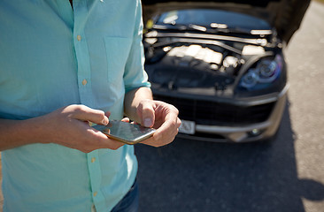 Image showing close up of man with smartphone and broken car