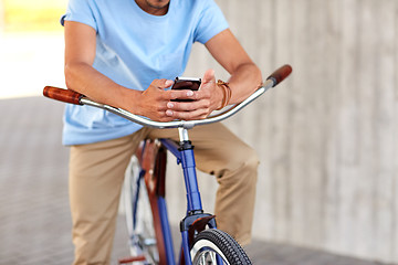 Image showing close up of man with smartphone and bike on street