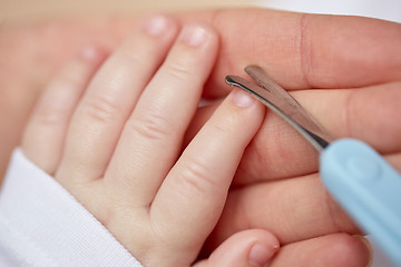 Image showing close up of hand with scissors trimming baby nails