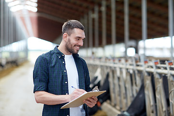 Image showing farmer with clipboard and cows in cowshed on farm