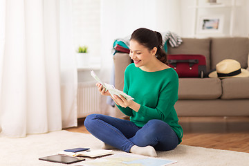 Image showing happy woman with money and travel map at home