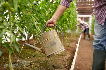 Image showing senior man with watering can at farm greenhouse