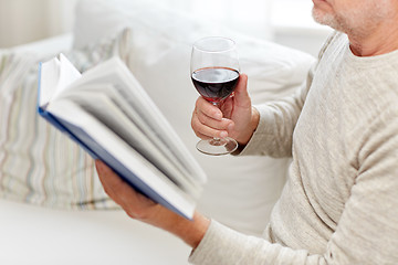 Image showing close up of senior man with wine reading book