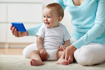 Image showing happy mother showing smartphone to baby at home