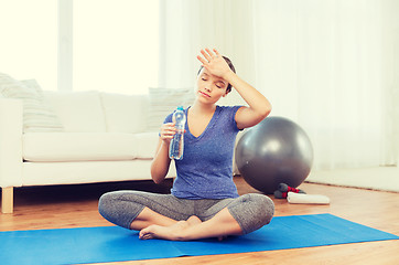 Image showing tired woman drinking water after workout at home