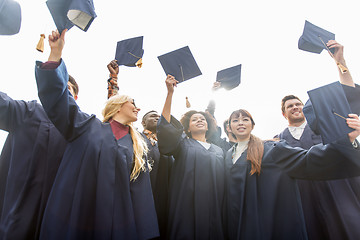 Image showing happy students or bachelors waving mortar boards