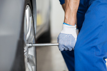 Image showing mechanic with screwdriver changing car tire