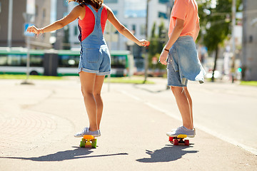 Image showing teenage couple riding skateboards on city street