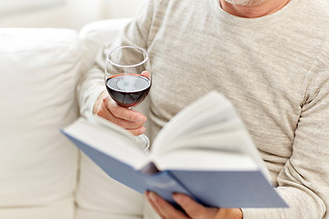 Image showing close up of senior man with wine reading book