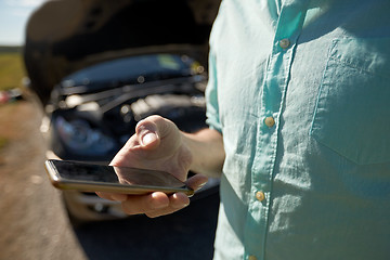 Image showing close up of man with smartphone and broken car