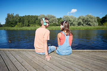 Image showing teenage couple with headphones on river berth