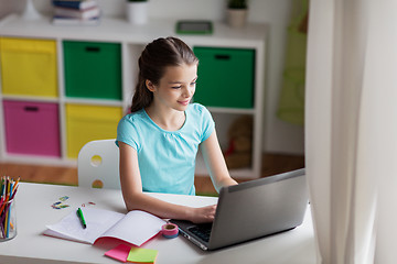 Image showing happy girl typing on laptop at home
