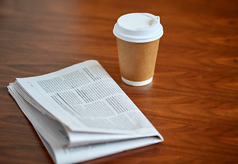 Image showing coffee drink in paper cup and newspaper on table