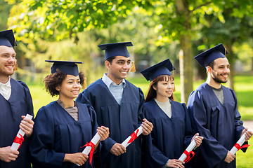 Image showing happy students in mortar boards with diplomas