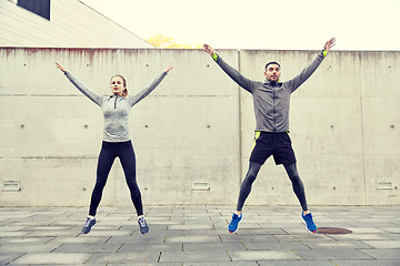 Image showing happy man and woman jumping outdoors