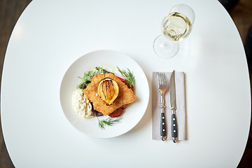 Image showing fish salad and wine glass on restaurant table