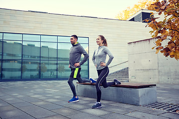 Image showing happy man and woman exercising on bench outdoors