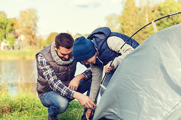 Image showing happy father and son setting up tent outdoors