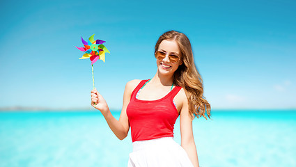 Image showing happy woman with pinwheel over blue sky and sea