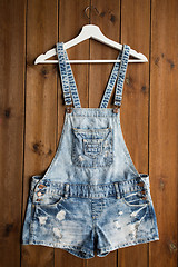 Image showing denim or jeans overalls with hanger on wood