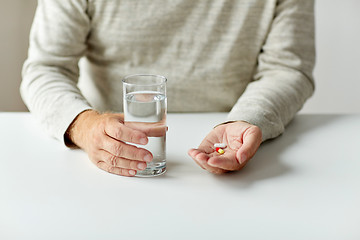 Image showing close up of hands with medicine pills and water