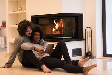 Image showing multiethnic couple used tablet computer on the floor