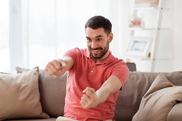 Image showing happy man holding something imaginary at home