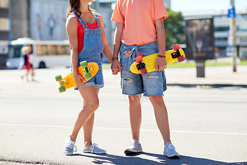 Image showing close up of young couple with skateboards in city