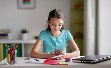 Image showing girl with smartphone distracting from homework