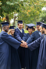 Image showing happy students in mortar boards with hands on top