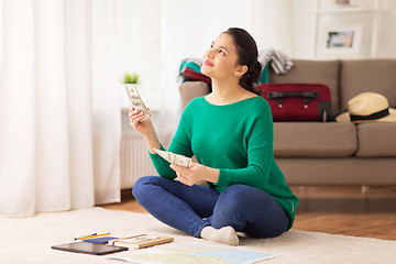 Image showing happy woman with money and travel map at home