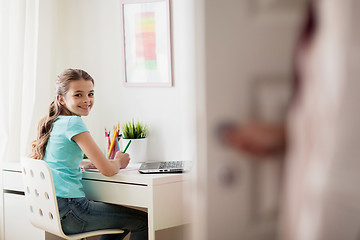 Image showing girl with laptop writing to notebook at home