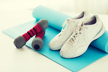 Image showing close up of sneakers, dumbbells and sports mat