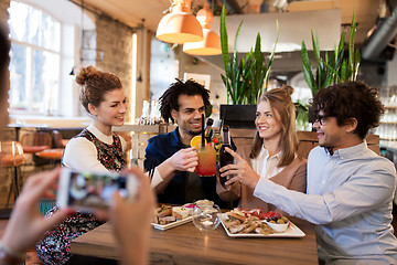 Image showing happy friends clinking drinks at bar or cafe