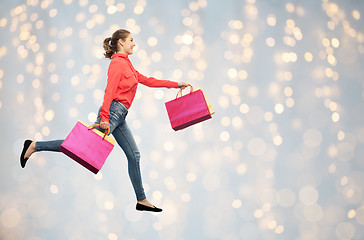 Image showing smiling young woman with shopping bags running