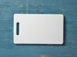 Image showing white plastic cutting board on blue table