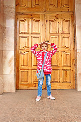 Image showing Schoolgirl posing before big wooden door
