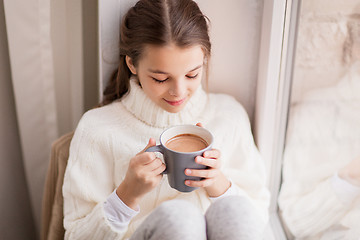 Image showing girl with cacao mug sitting at home window