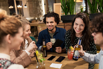 Image showing friends with drinks, money and bill at bar