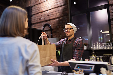 Image showing woman taking paper bag from seller at cafe