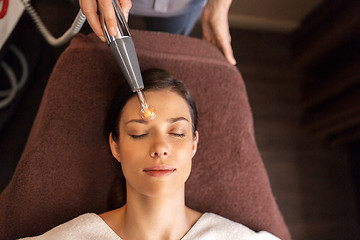 Image showing woman with microcurrent face massager in spa