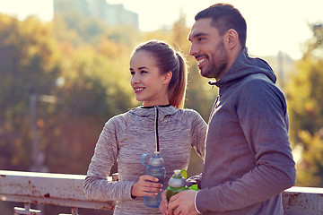 Image showing smiling couple with bottles of water outdoors