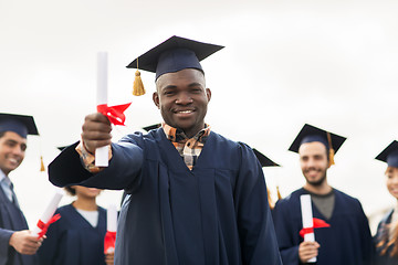 Image showing happy students in mortar boards with diplomas