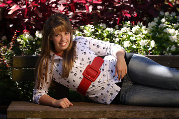 Image showing Pretty Teenage Girl Lying on a Park Bench