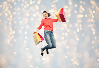 Image showing smiling young woman with shopping bags jumping