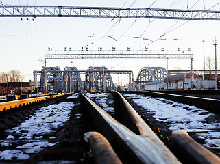 Image showing landscape with railway with trains, lot of steel rafters at sunset