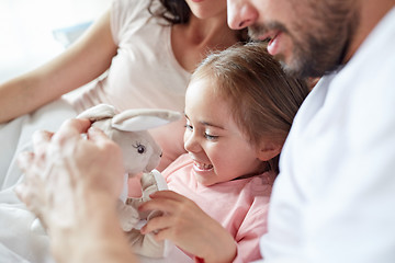 Image showing happy child with toy and parents in bed at home