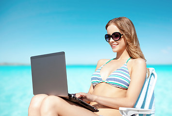 Image showing woman with laptop sunbathing in lounge on beach